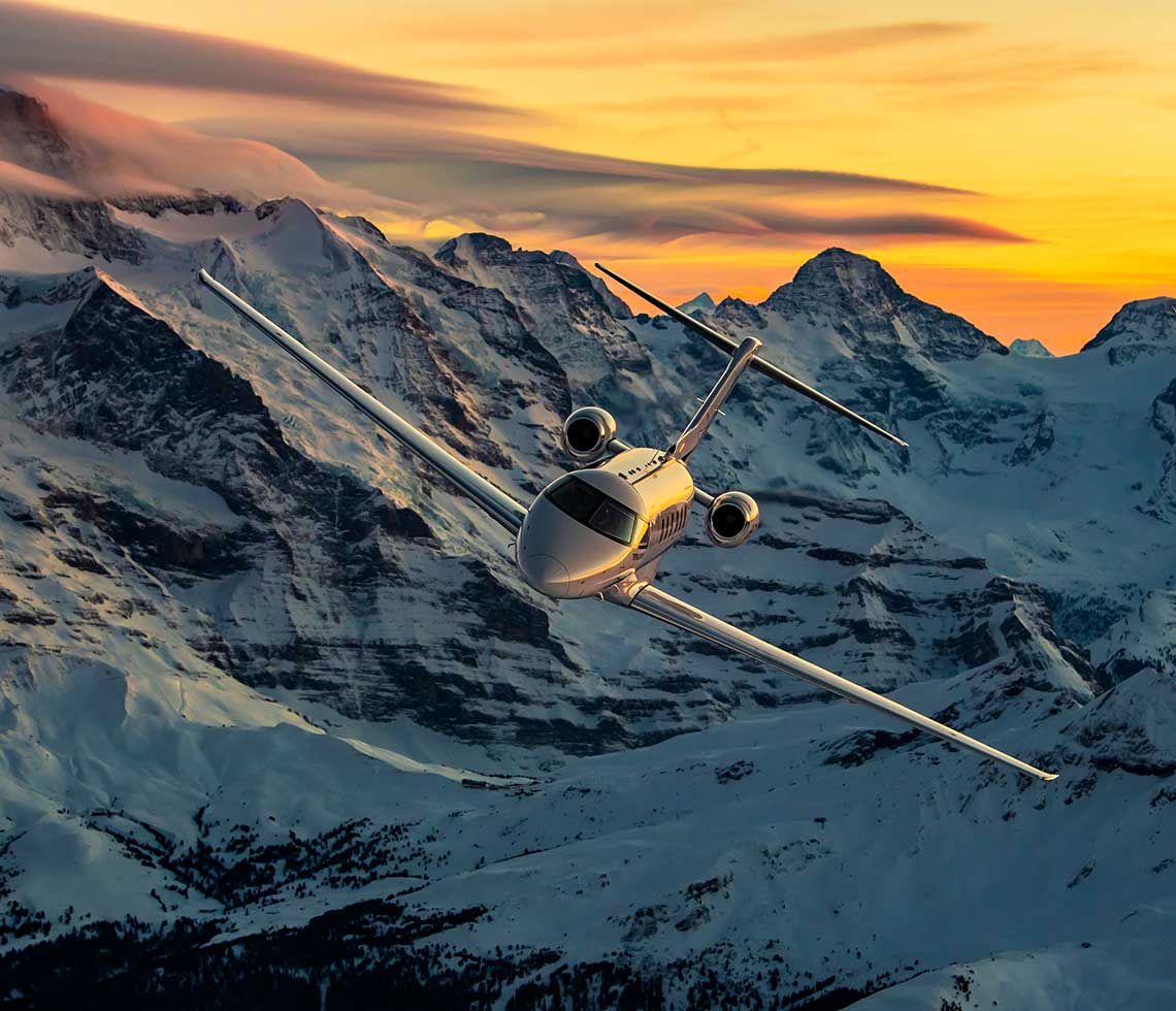 Pilatus PC-24 jet flying by snow-covered mountains