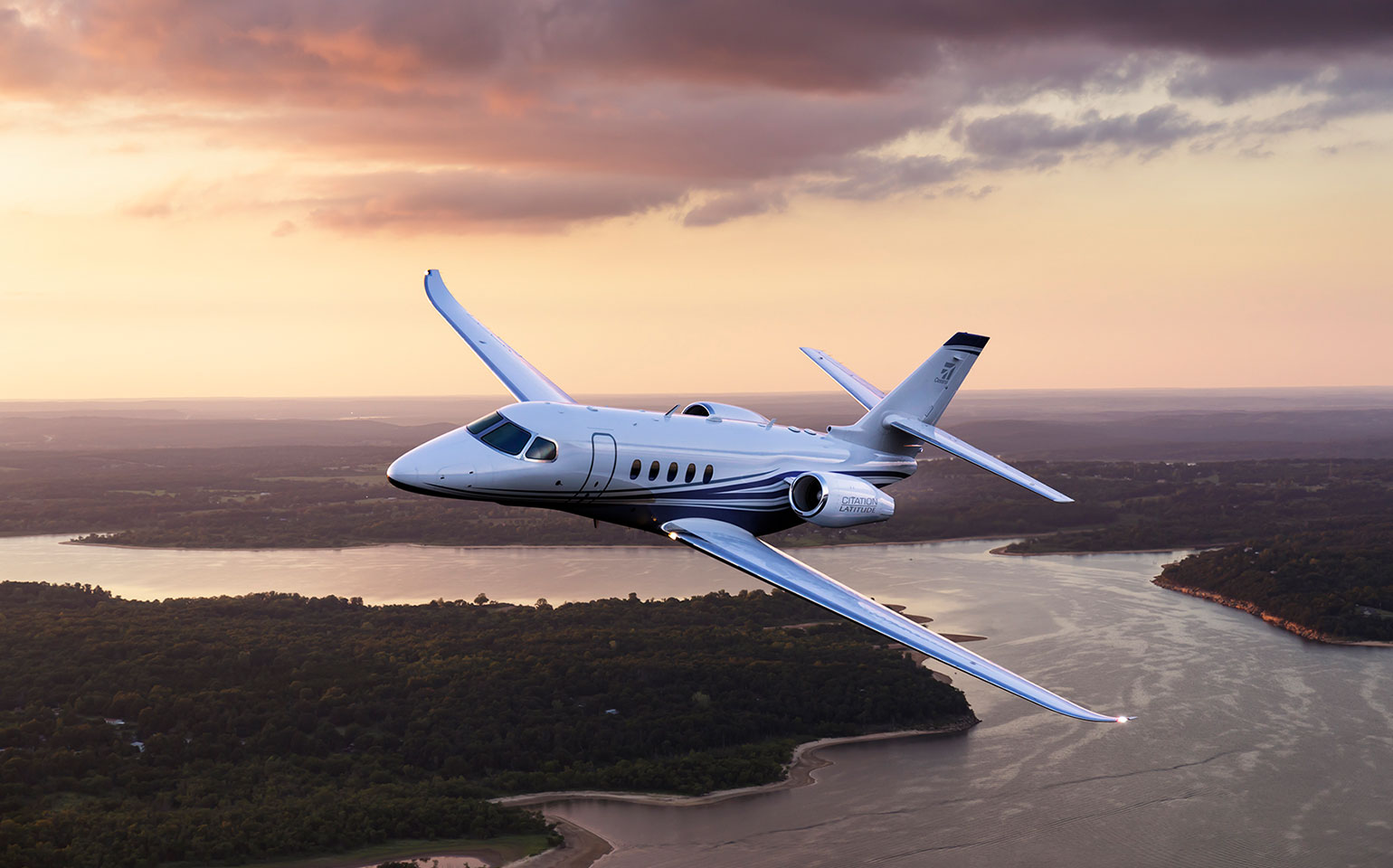 Cessna Citation Latitude private jet charter flying over river